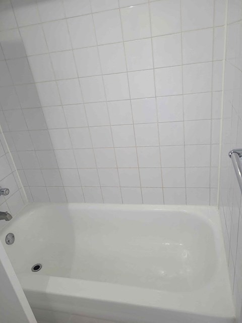 a white tub in a bathroom with white tiled walls