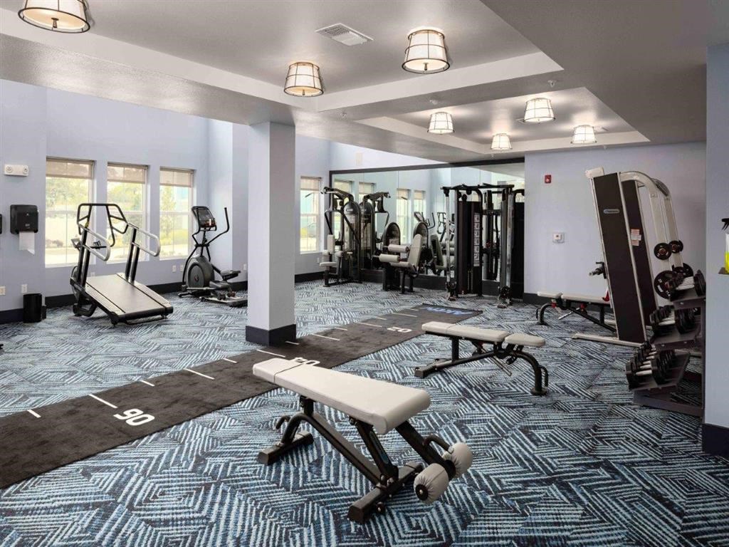 a gym with weights and exercise equipment in a building with windows