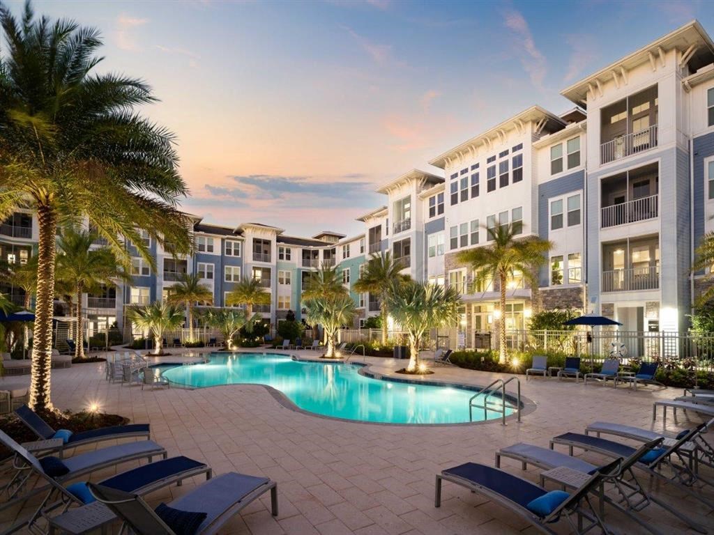 a swimming pool in front of an apartment building at sunset
