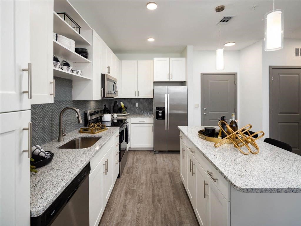 A modern kitchen with white cabinets and a granite countertop.