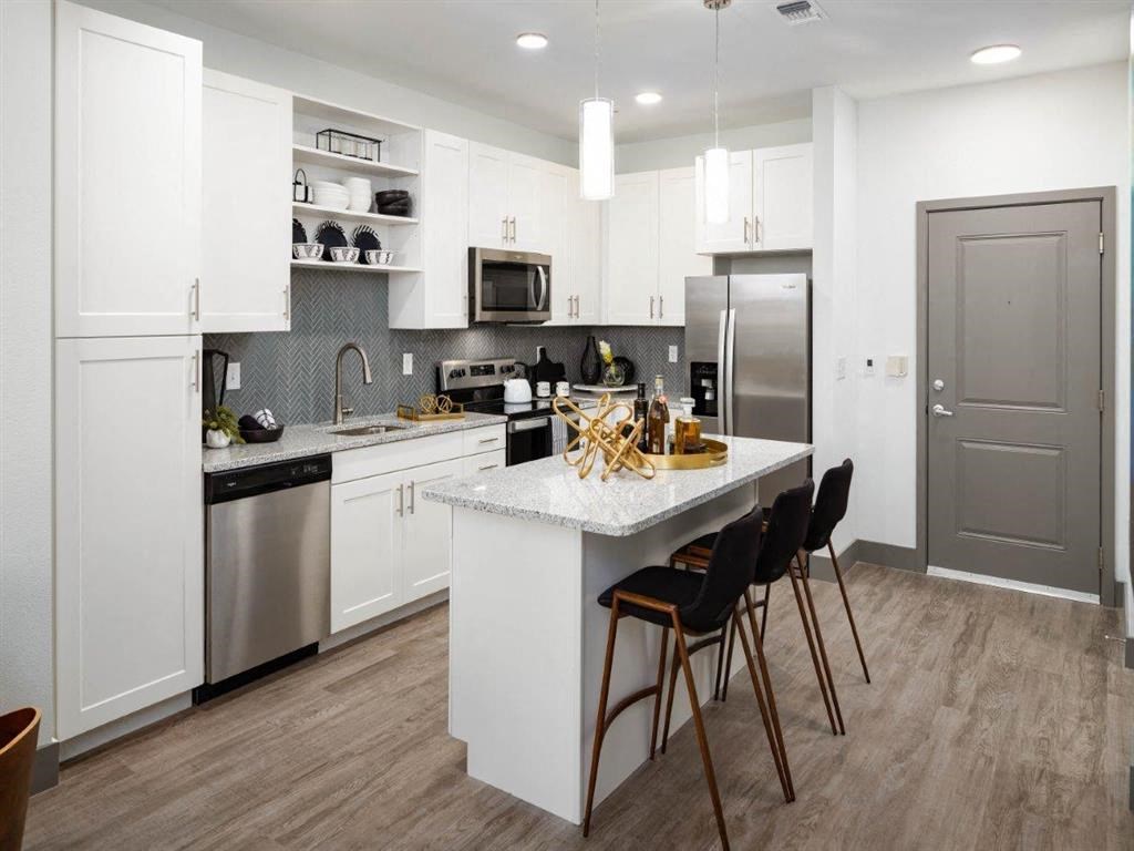 a large kitchen with white cabinets and stainless steel appliances