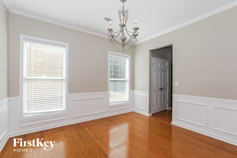 a dining room with wood floors and white walls and a chandelier