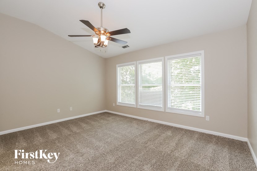 a living room with a ceiling fan and three windows