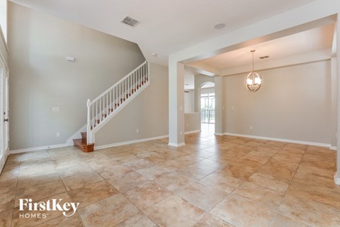 a large empty living room with a staircase and a tile floor