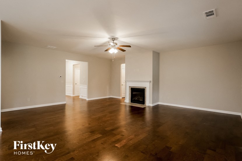 the living room of an empty house with a ceiling fan and a fireplace