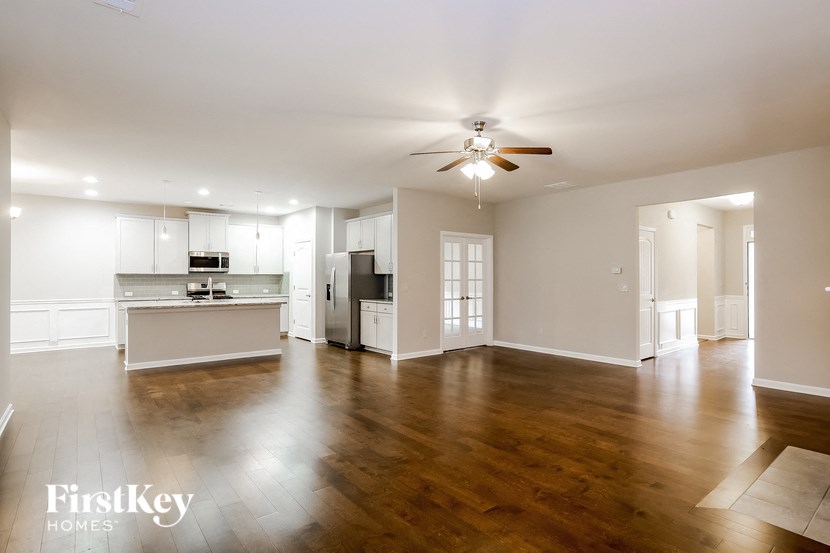 an empty living room and kitchen with a ceiling fan