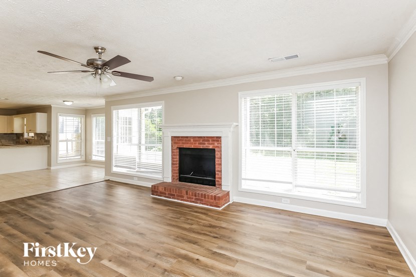 an empty living room with a fireplace and a ceiling fan