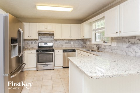 a kitchen with white cabinets and a marble counter top