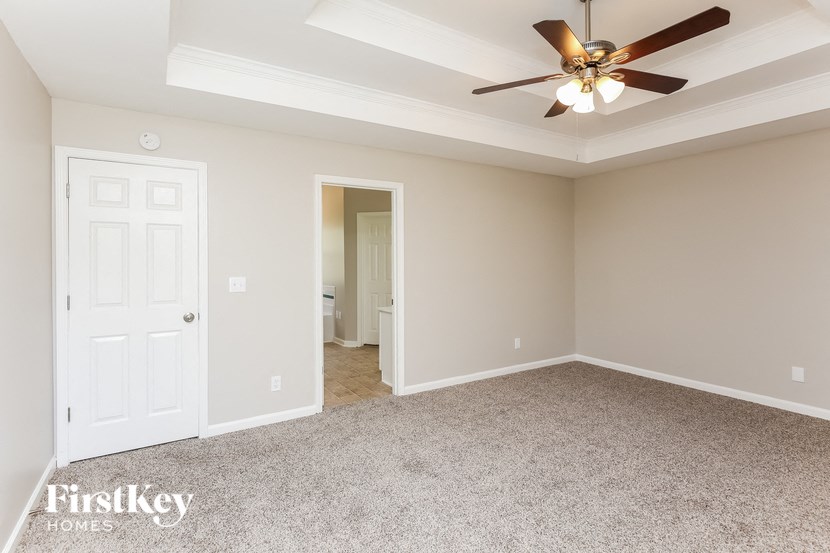 a bedroom with a ceiling fan and a door to a bathroom