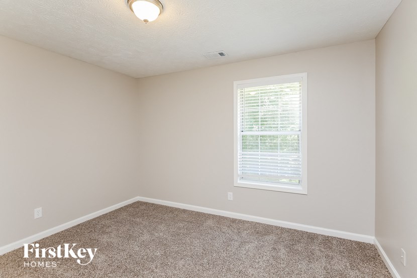 a bedroom with a window and a carpeted floor