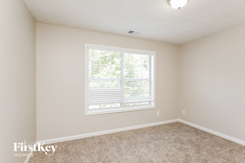 a bedroom with a large window and a carpeted floor