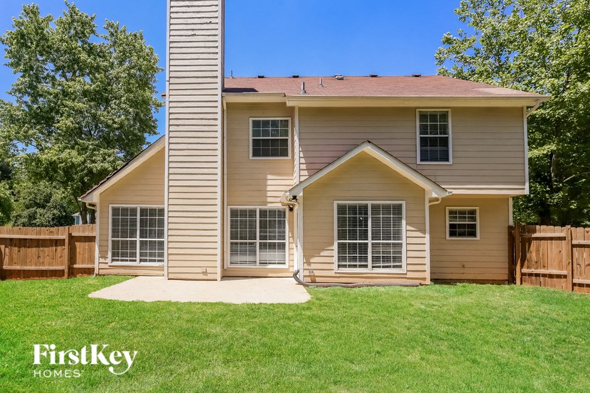 a tan house with a yard and a wooden fence