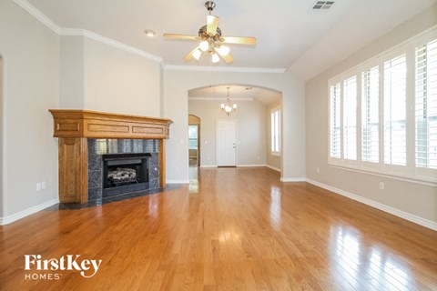 A spacious room with a fireplace and wooden floors.