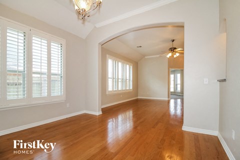 A well-lit room with wooden floors and a chandelier.