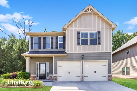 A two-story house with a garage is showcased in the image.