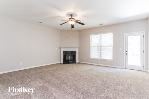 A spacious room with a fireplace and a ceiling fan.