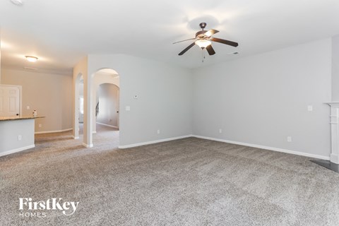 A spacious room with a ceiling fan and carpeted floor.