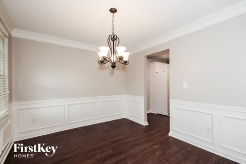 a dining room with white walls and wood flooring and a chandelier