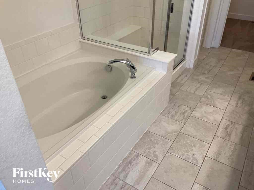 a bath tub with a shower in a bathroom with tiled floors