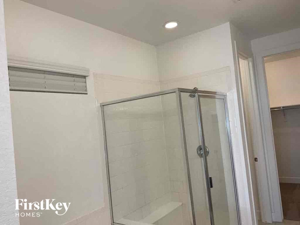 a small shower in a white bathroom with a glass door