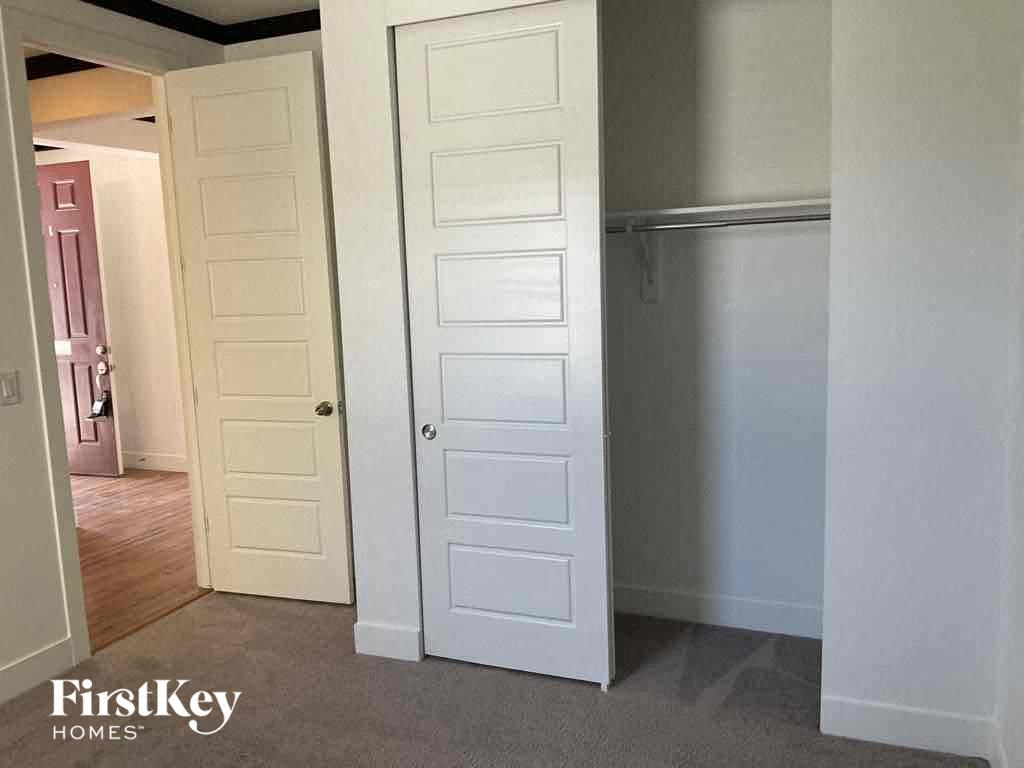 an open white closet door in a room with a hallway