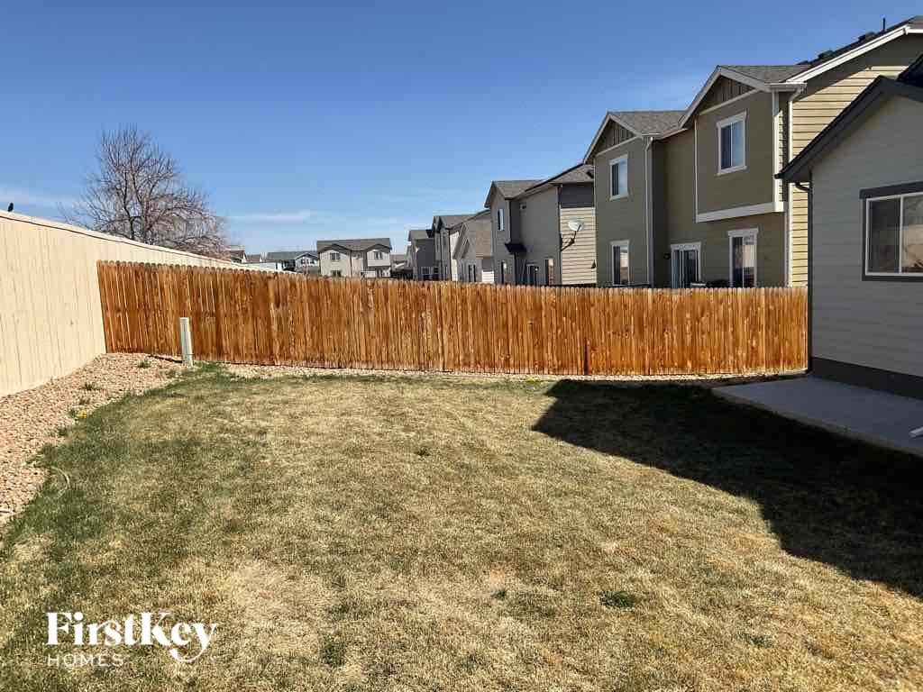 a wooden fence in a backyard with houses behind it