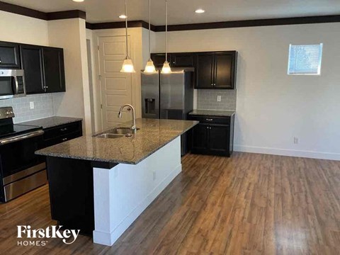 an open kitchen with black cabinets and a granite counter top