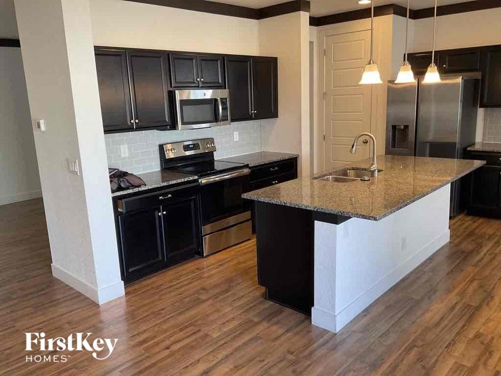 an updated kitchen with black cabinets and a granite counter top
