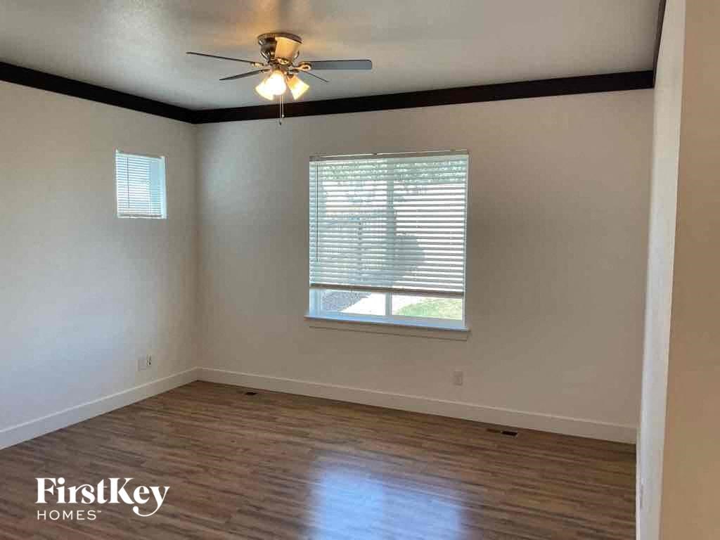 an empty living room with a ceiling fan and a window