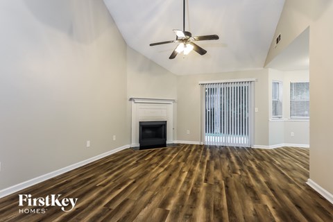 A spacious room with a fireplace and wood flooring.