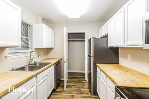 A kitchen with white cabinets and a wooden counter top.