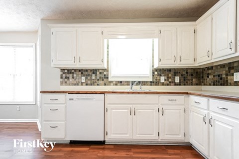 a white kitchen with white cabinets and a window
