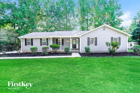 a small white house with a lawn and trees