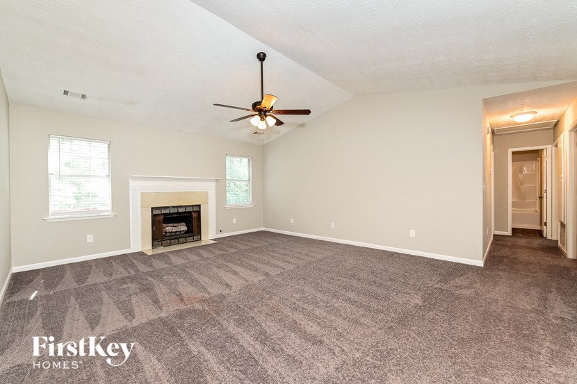 the living room has a fireplace and a ceiling fan