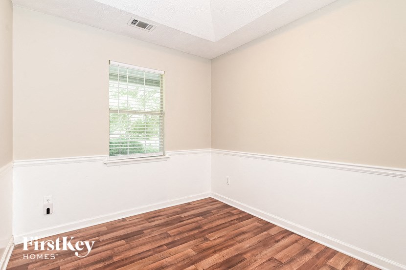 a bedroom with wood flooring and white walls and a window