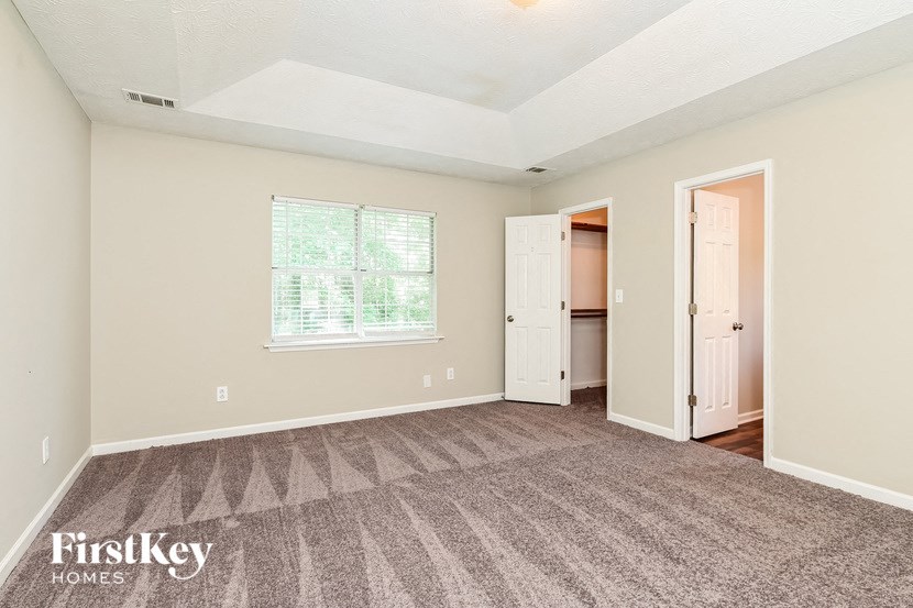 an empty living room with carpet and a door to a closet