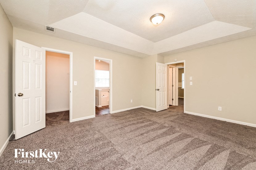 a living room with carpet and a door to a bathroom