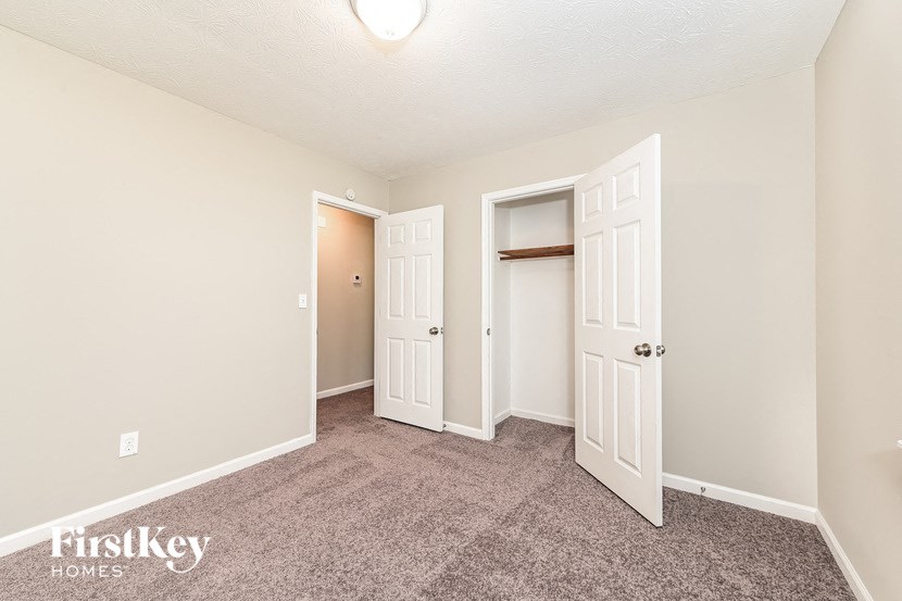 a bedroom with carpeted flooring and white closet and doors