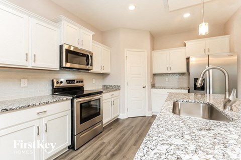 A kitchen with white cabinets and a granite counter top.