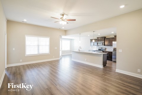 A spacious kitchen and living room with wood flooring and a ceiling fan.