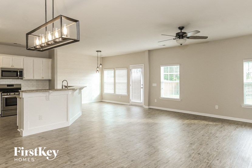 an empty kitchen and living room with a ceiling fan