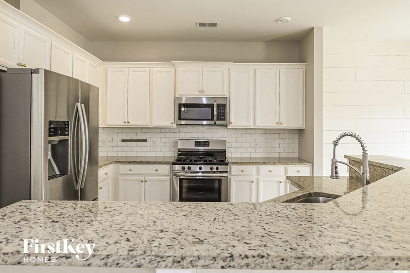 a kitchen with white cabinets and a marble counter top