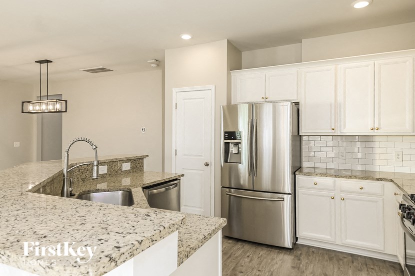 a kitchen with granite counter tops and a stainless steel refrigerator