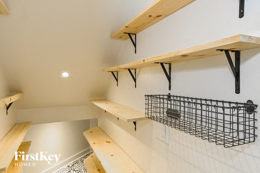 a laundry room with wooden shelves and a wire basket on the wall