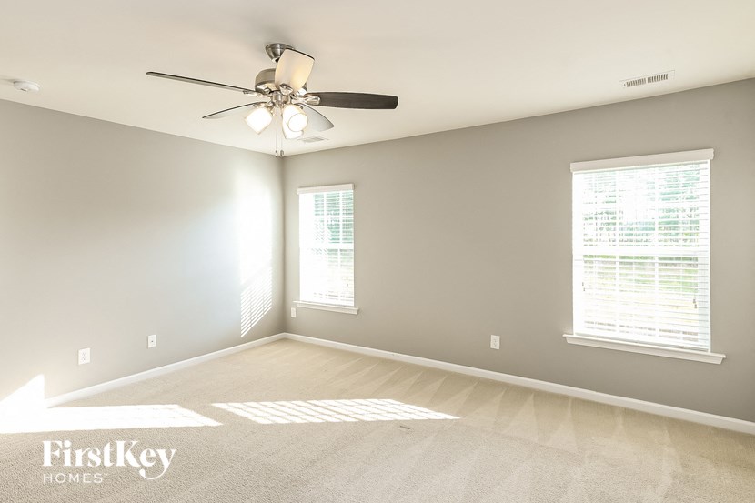 an empty room with a ceiling fan and two windows