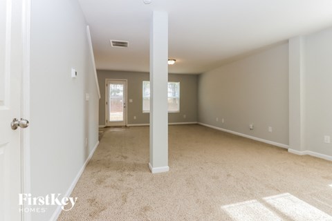 A spacious room with a carpeted floor and white walls.