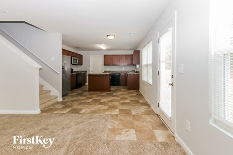 A spacious kitchen with a checkered floor and a staircase on the left.