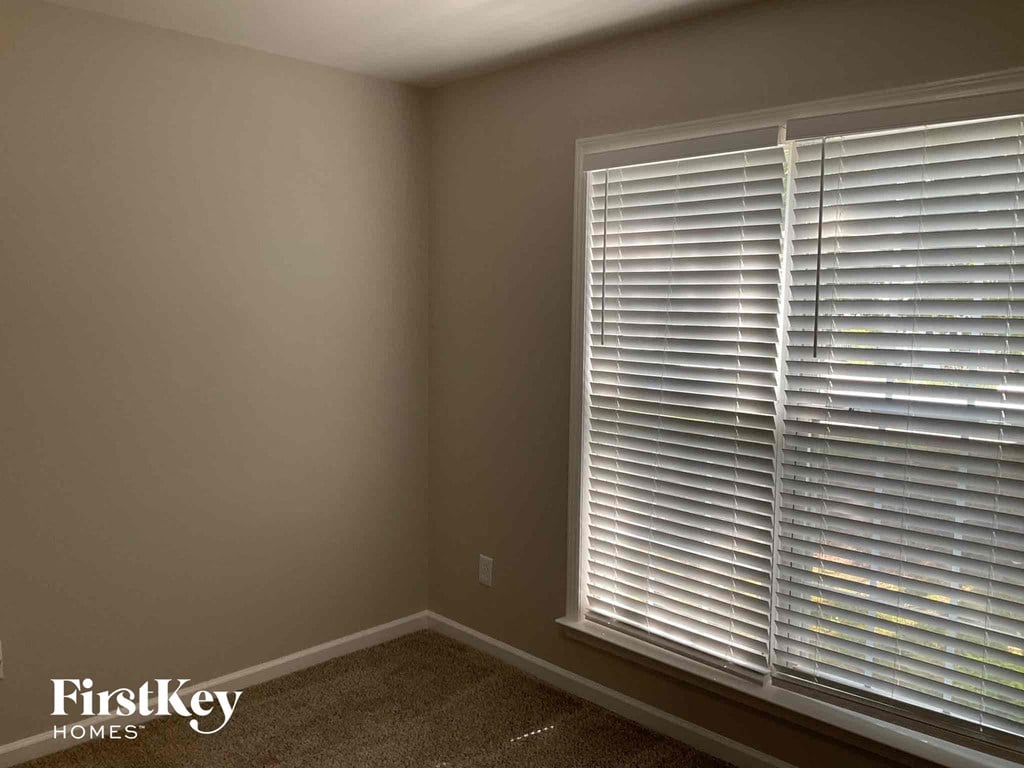 a bedroom with a large window with white blinds