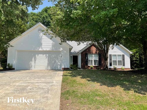 a white and brick house with a garage and trees