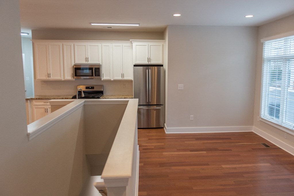a kitchen with white cabinets and a hard wood floor